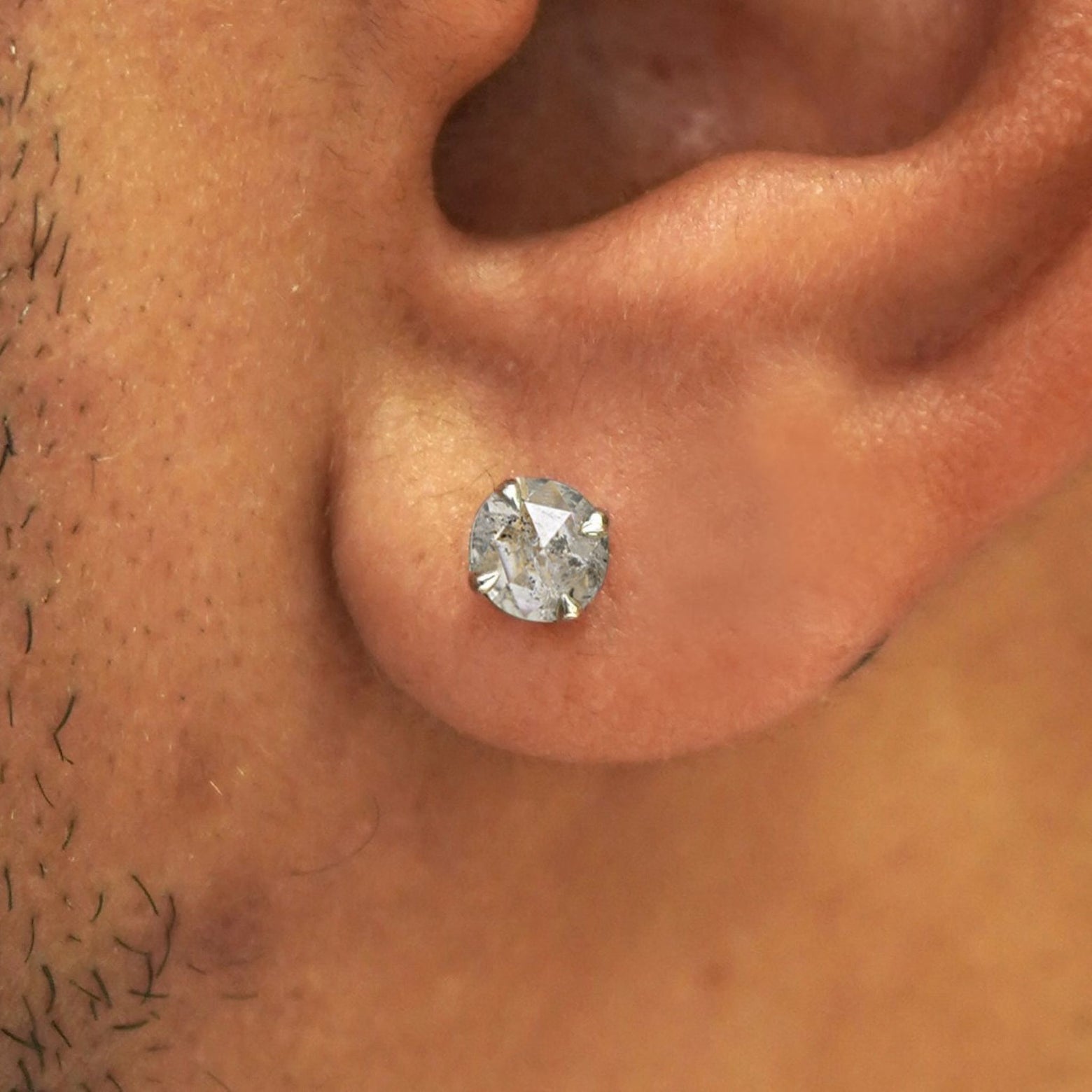 Close up view of a model's ear wearing a solid 14k gold salt and pepper diamond pressure lock earring