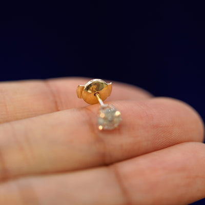 A Salt and Pepper Diamond Pressure Lock Earring tilted on a model's fingertip to show the pressure lock backing on the post