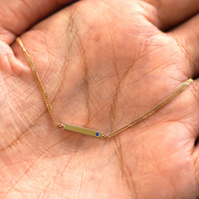 A yellow gold sapphire Gemstone Bar Bracelet draped on a model's palm