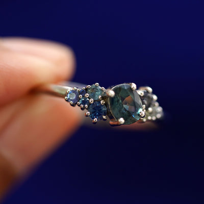 A model holding a Sapphire Cluster Ring tilted to show the details of the gemstone cluster