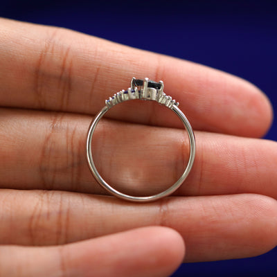 A white gold Sapphire Cluster Ring in a model's hand showing the thickness of the band