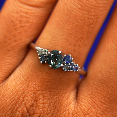 Close up view of a model's fingers wearing a 14k white gold Sapphire Cluster Ring