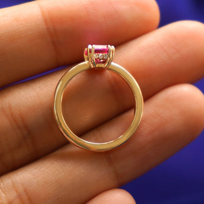 A Emerald Cut Pink Sapphire Ring in a model's hand showing the thickness of the band and the height of the ring