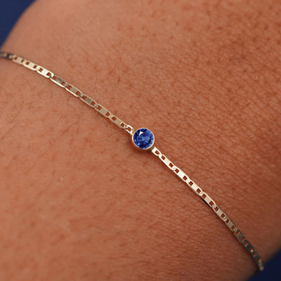 Close up view of a models wrist wearing 14k yellow gold Sapphire Bracelet