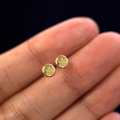 A model's hand holding a pair of recycled 14k gold Screw Earrings