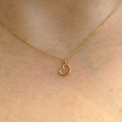 Close up view of a model's neck wearing a 14k yellow gold Heart Necklace