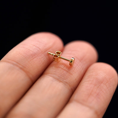A 14k gold Small Circle Earring sitting sideways on a model's fingertips to show detail
