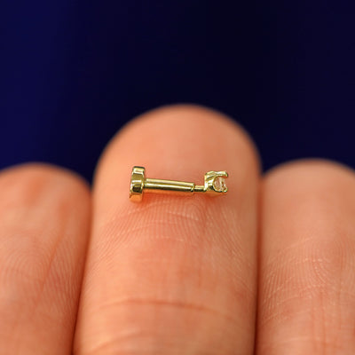 Side view of a yellow gold 2mm Diamond Flatback Piercing on a model's fingertips