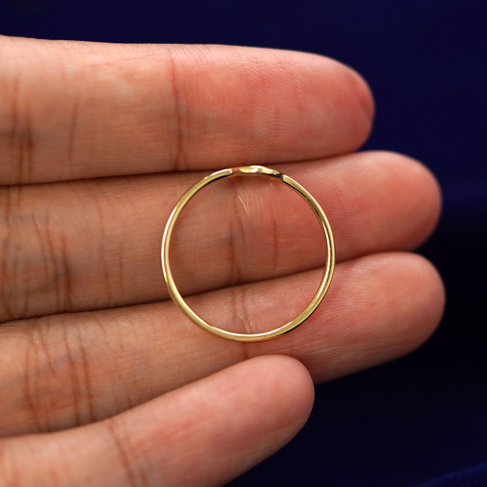 A yellow gold Heart Ring in a model's hand showing the thickness of the band