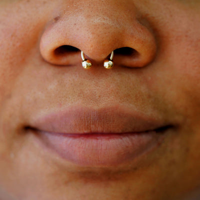 A model wearing a 14k solid gold Small Horseshoe piercing in their septum