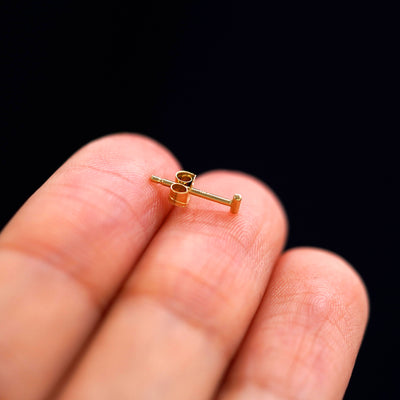 A 14k gold Small Line Earring sitting sideways on a model's fingertips to show detail