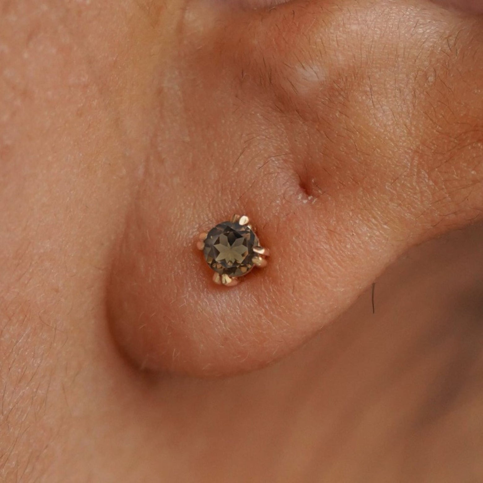 Close up view of a model's ear wearing a 14k yellow gold Smokey Quartz Earring