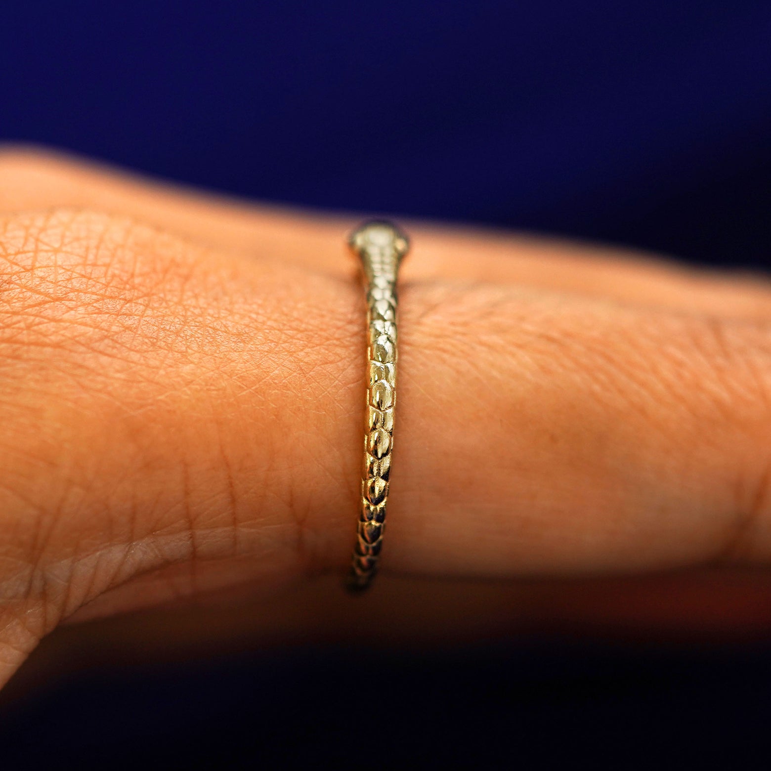 Alternate Side view of an Ouroboros Snake Ring on a model's finger showing the back of the snake's head 