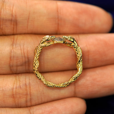 A yellow gold rose cut diamond Guardian Snakes Ring in a model's hand showing the thickness of the band