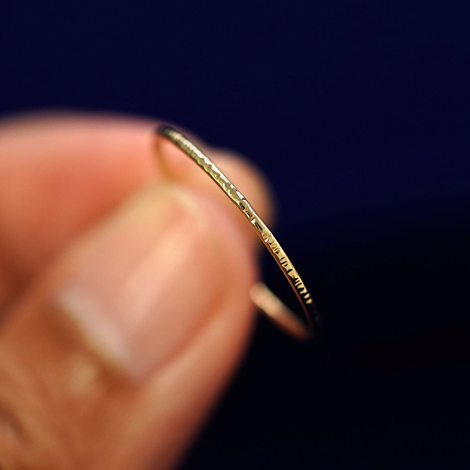 A model holding a Shimmer Ring tilted to show the side of the ring