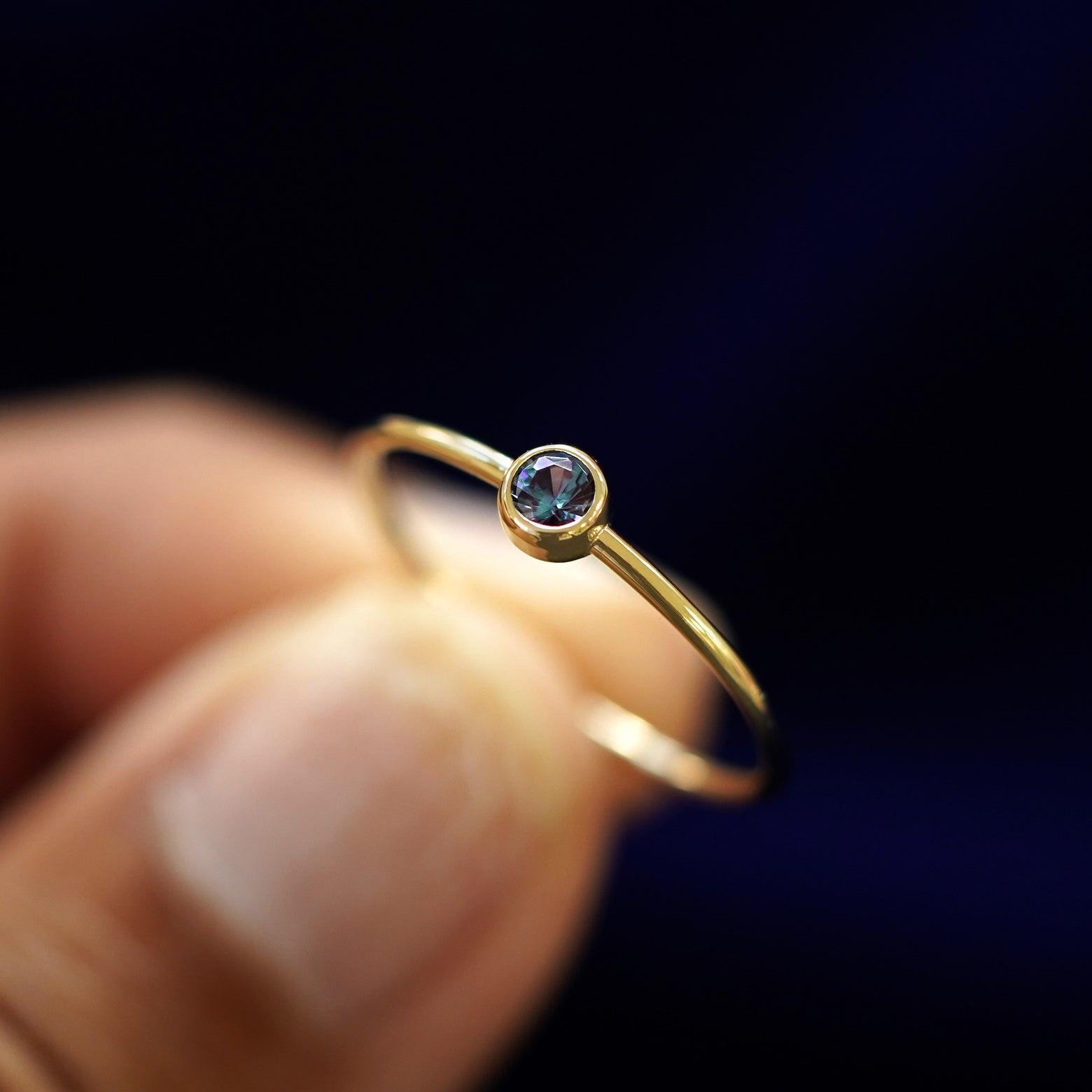 A model holding an Alexandrite Ring tilted to show the bezel setting