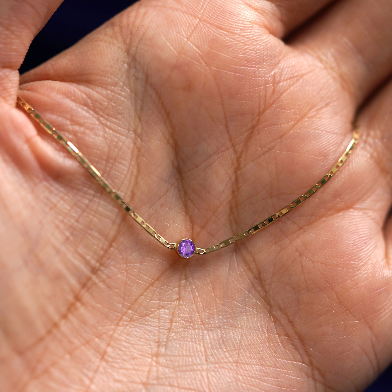 A yellow gold Amethyst Bracelet draped on a model's palm