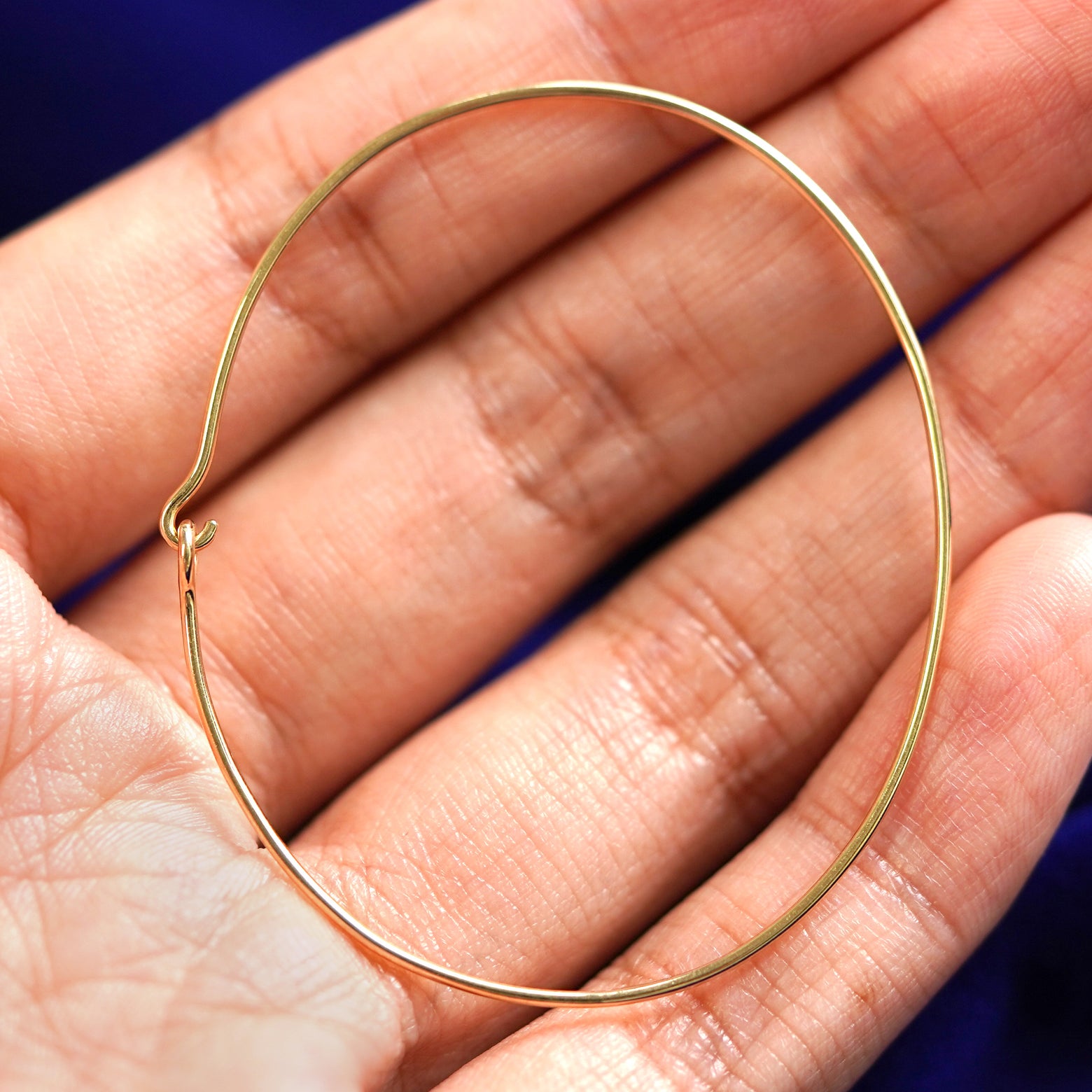 A yellow gold Line Bangle Bracelet sitting in a model's palm