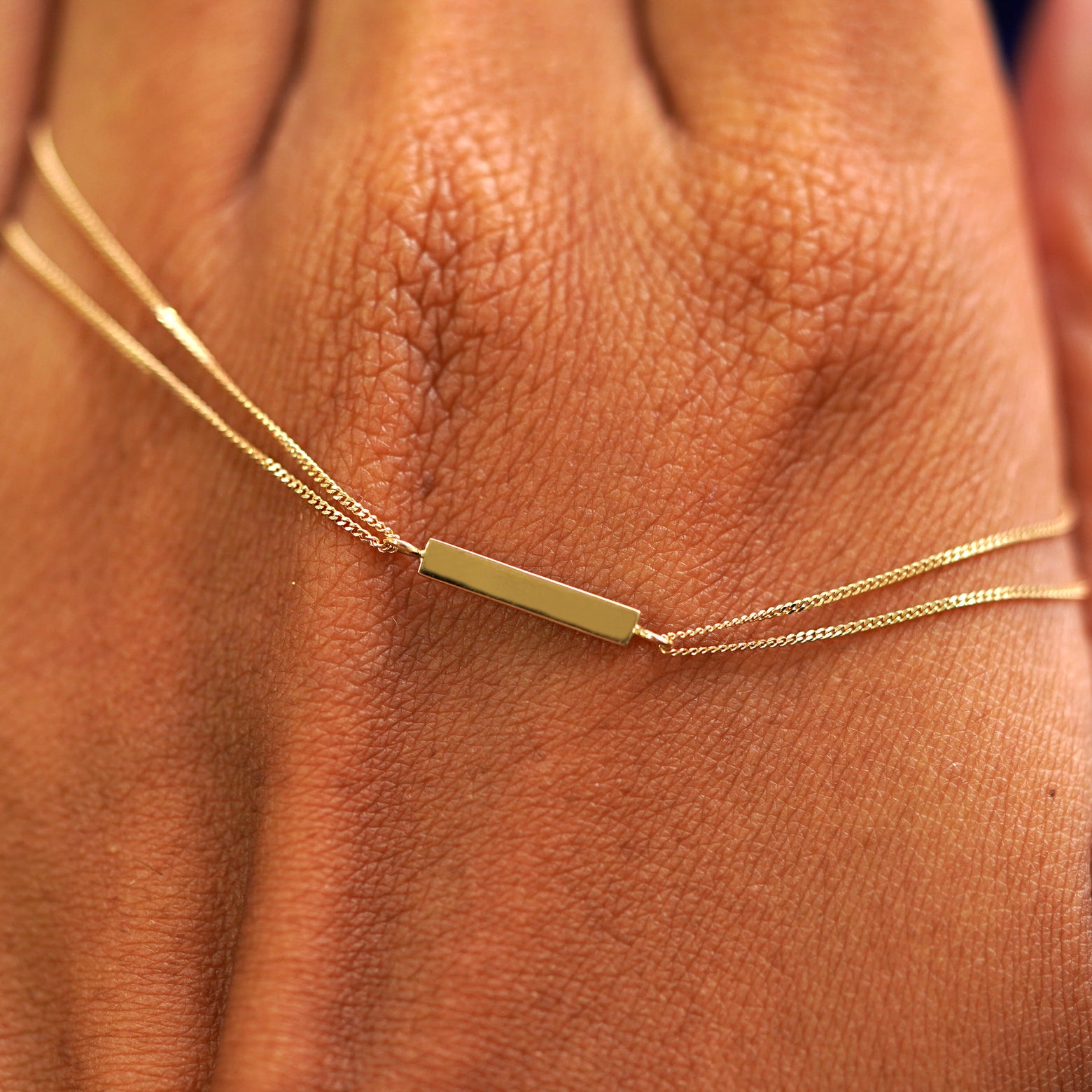 A solid gold Bar Bracelet resting on the back of a model's hand