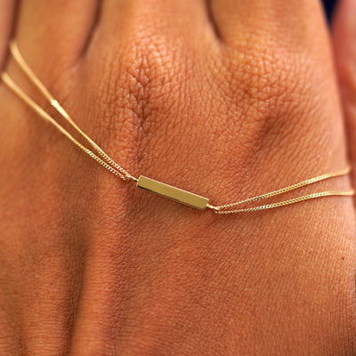 A solid gold Bar Bracelet resting on the back of a model's hand