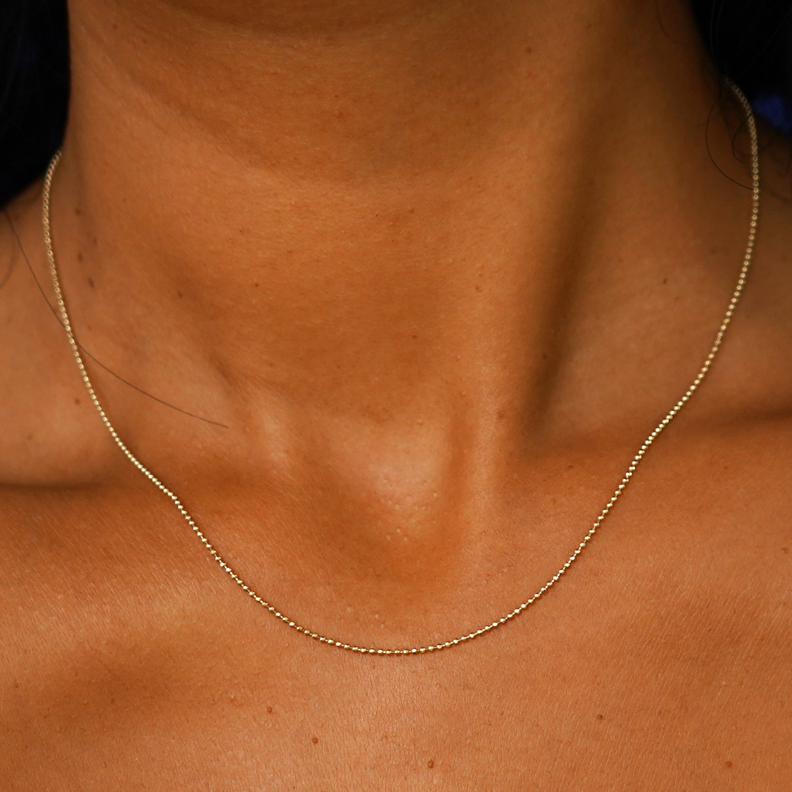 Close up view of a model's neck wearing a solid yellow gold Bead Necklace