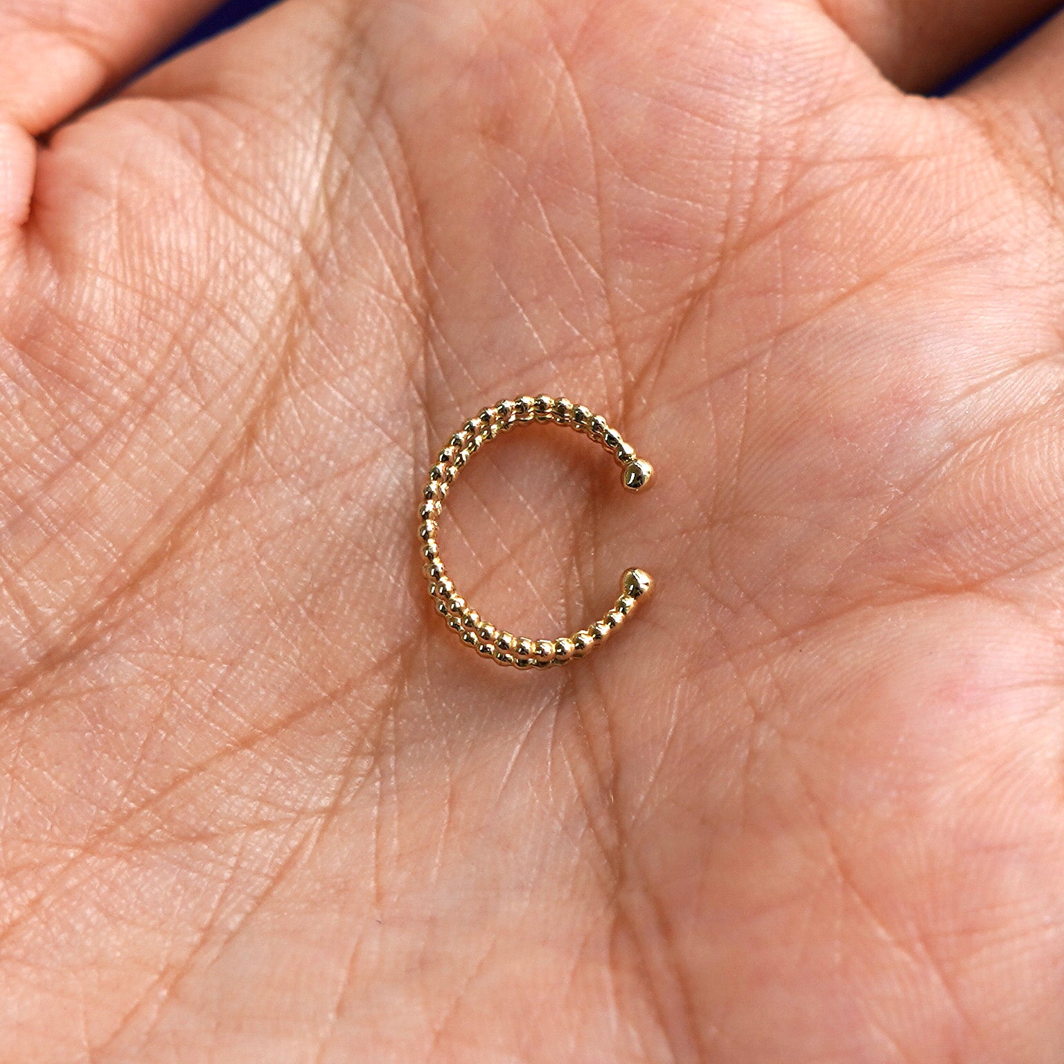 Alternate view of a solid yellow gold Beaded Cuff earring  in a model's palm