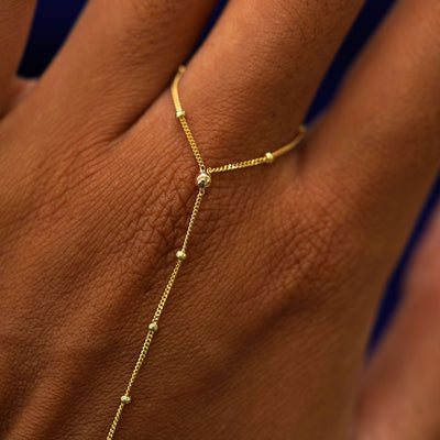 Close up view of a model's hand showing the Beaded Essential Hand Bracelet on their middle finger