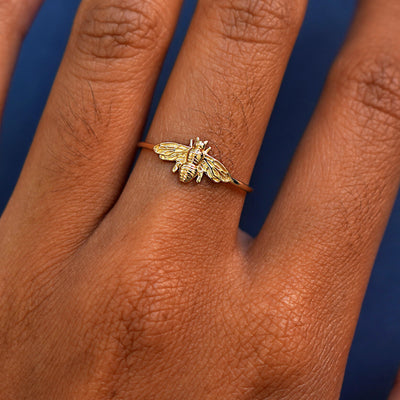 Close up view of a model's hand wearing a 14 karat gold Bee Ring