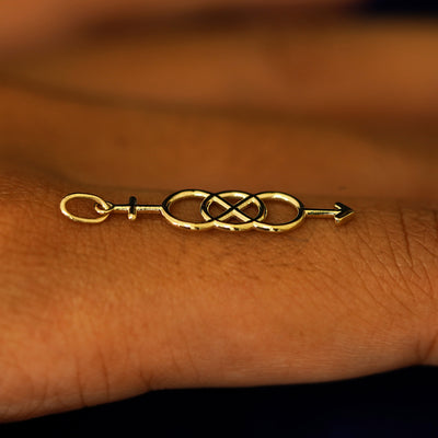 A 14k solid gold Bisexual Symbol Charm for chain balancing on the back of a model's finger