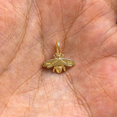 A solid gold Bee Charm for chain resting in a model's palm to show the underside of the charm