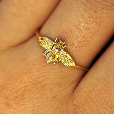 Close up view of a model's fingers wearing a solid yellow gold Bee Ring