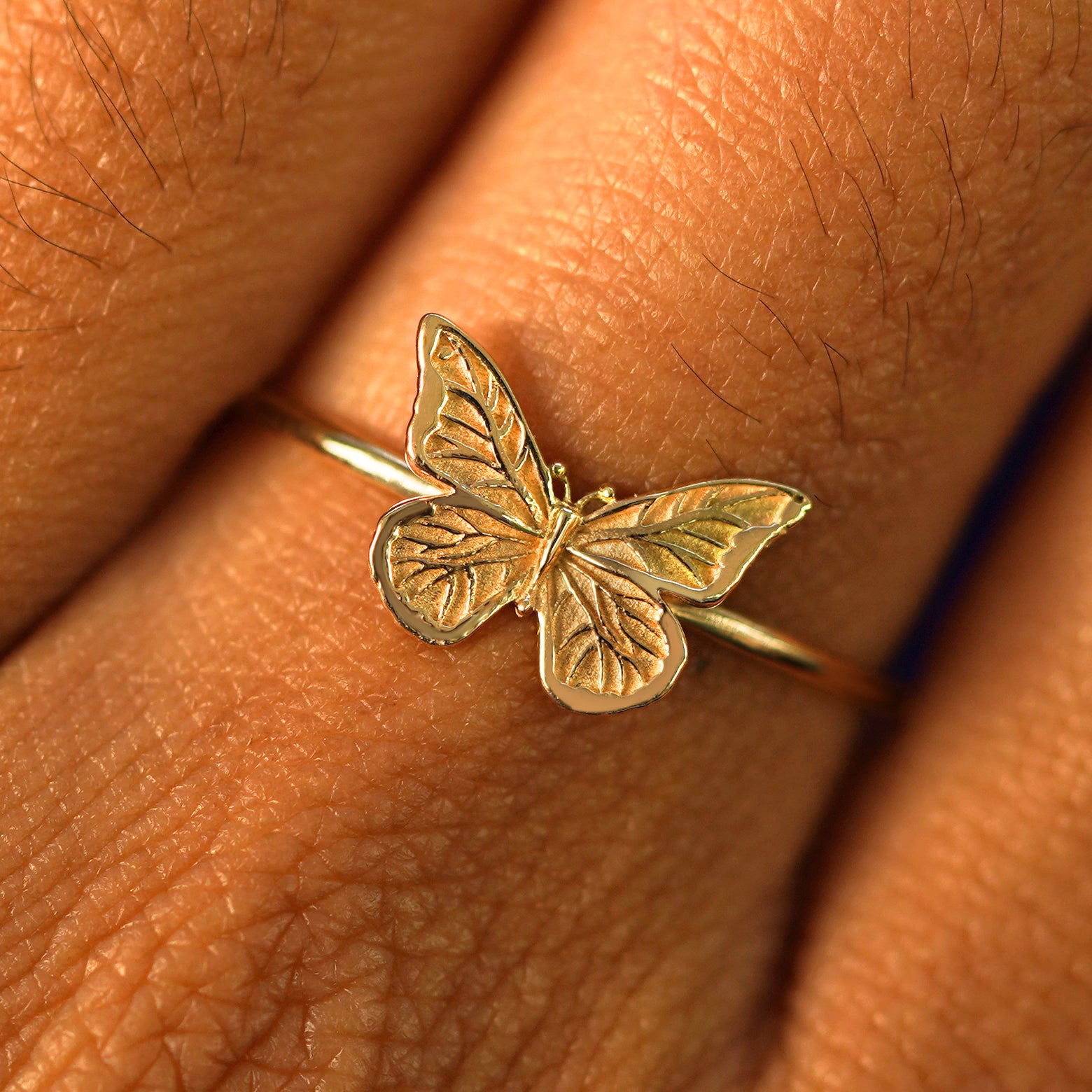 Close up view of a model's fingers wearing a yellow gold Butterfly Ring