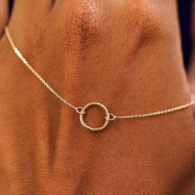 A solid gold Lockless Cable Necklace resting on the back of a model's hand