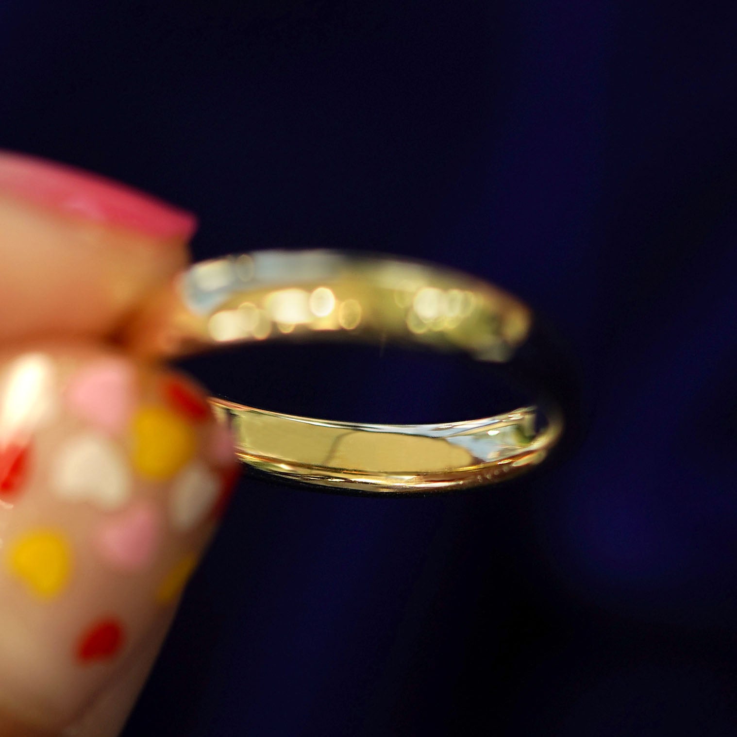 A model holding a 14k gold Mix Mirror Band tilted to show the inside of the band