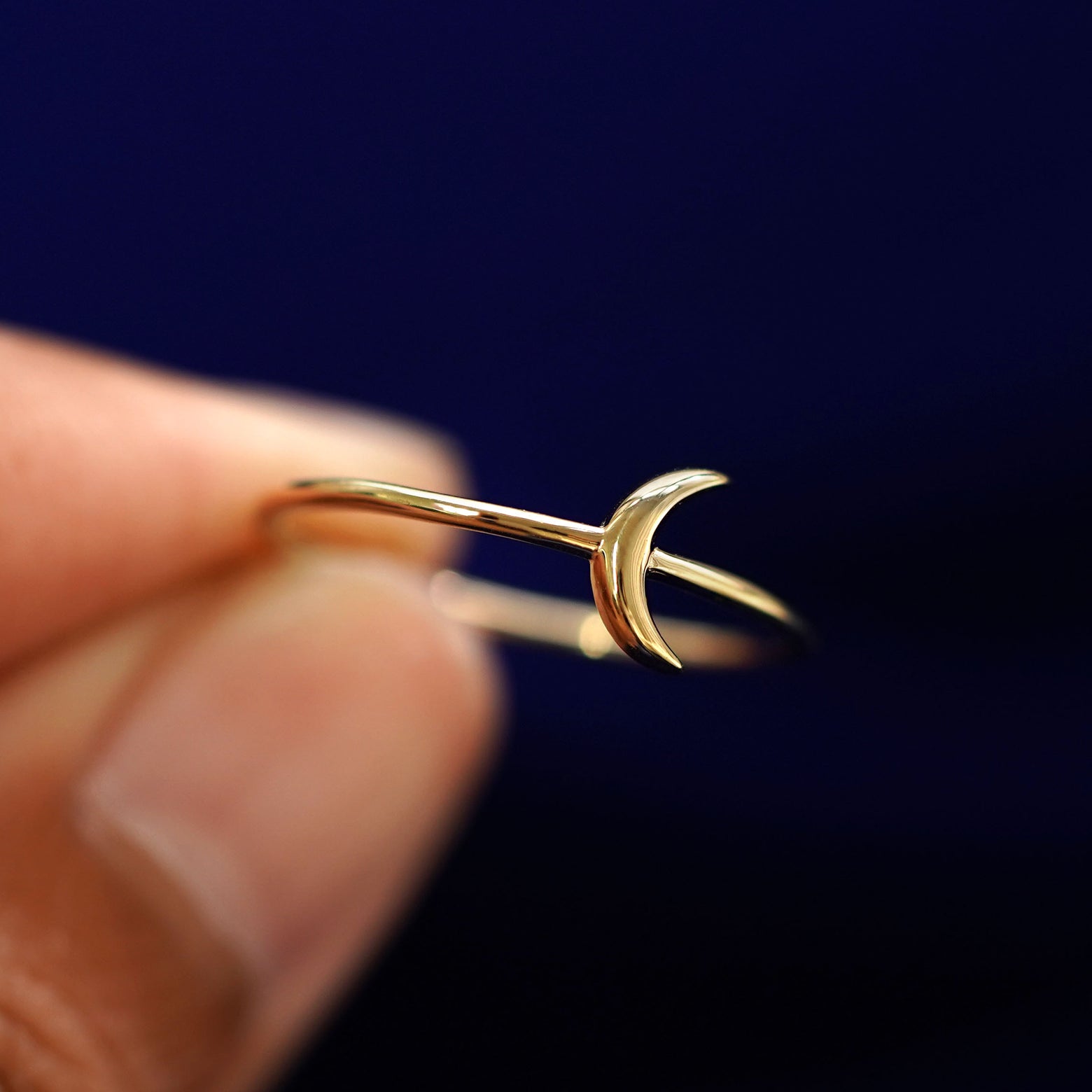 A model holding a Moon Ring tilted to show the side of the ring