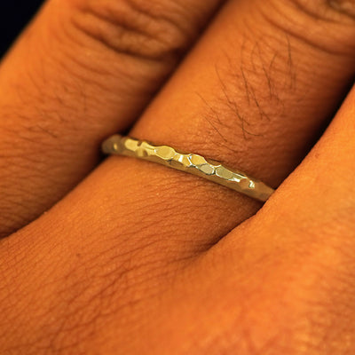 Close up view of a model's fingers wearing a 14k yellow gold Curvy Hammered Band