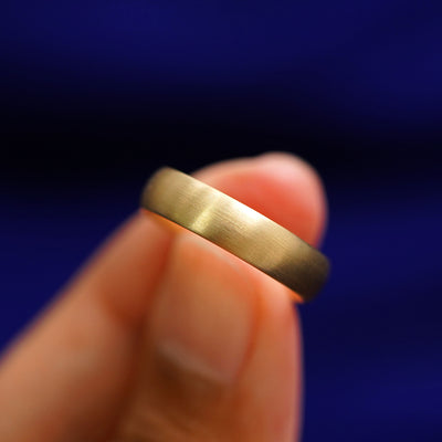 A model holding a Curvy Matte Band tilted to show the side of the ring