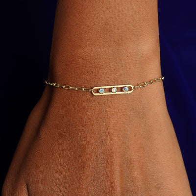 Close up view of a model's wrist wearing a yellow gold Dancing Gemstone Bracelet with three Opals