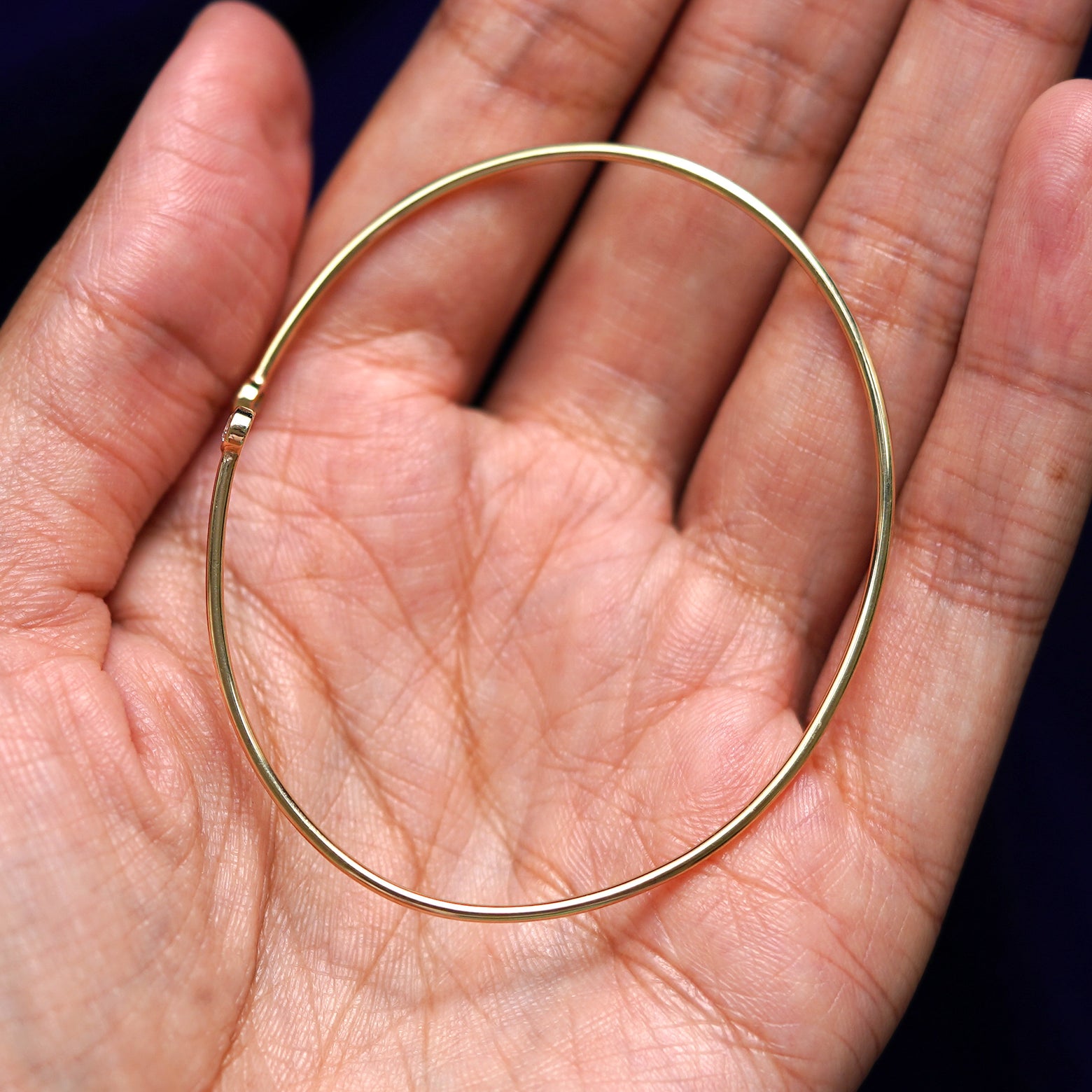 A yellow gold Diamond Bypass Bracelet sitting in a model's palm