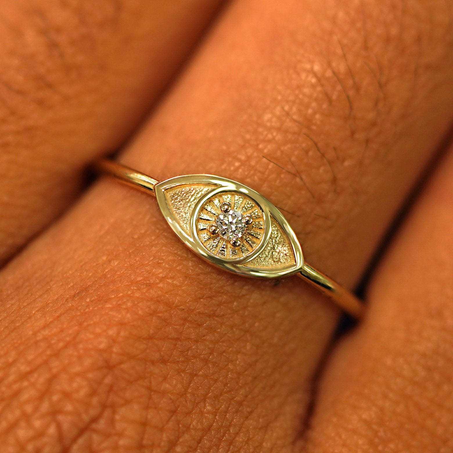 Close up view of a model's hand wearing a yellow gold Diamond Evil Eye Ring