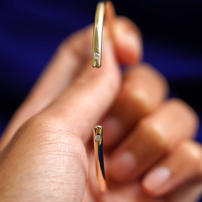 A model holding a 14k yellow gold Diamond Open Bangle Bracelet to show the gap in the bangle