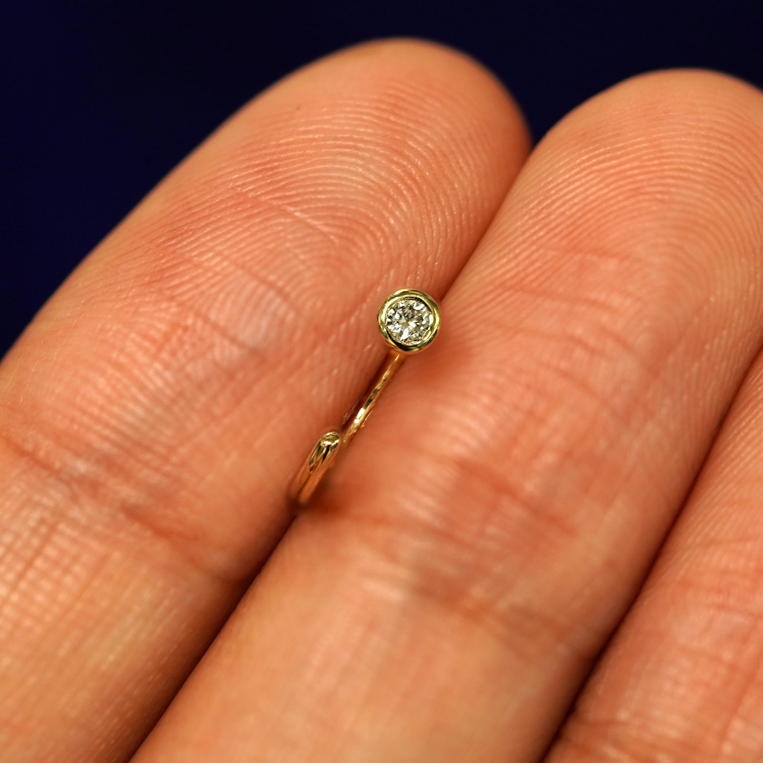 A Diamond Open Hoop between a models fingers to show the detail of the bezel set stone