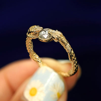 A model holding a salt and pepper diamond intertwined snakes ring between their fingertips to show the detials of the snakes