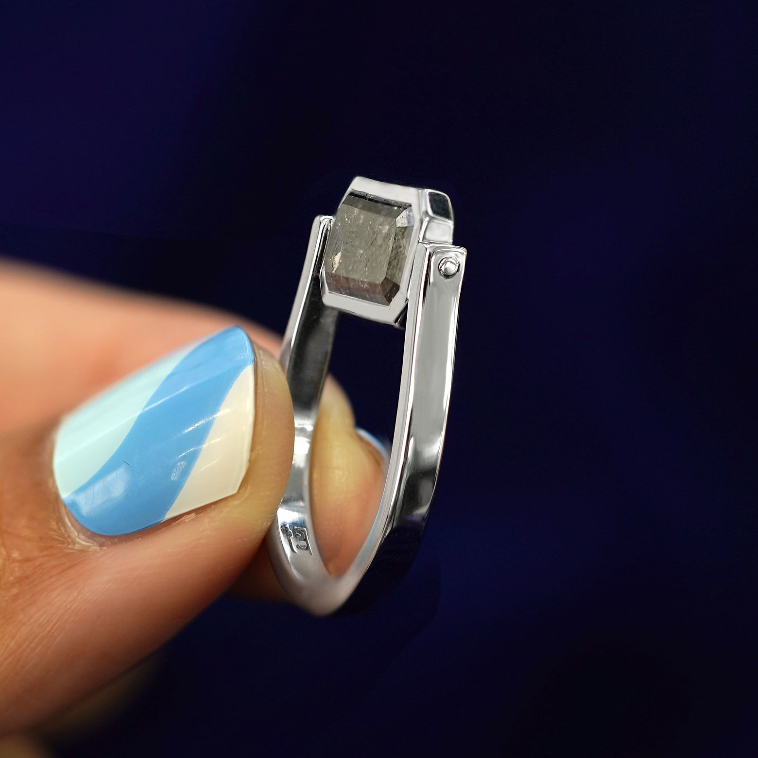 A model holding a salt and pepper diamond spinner ring between their fingertips with the diamond spun up