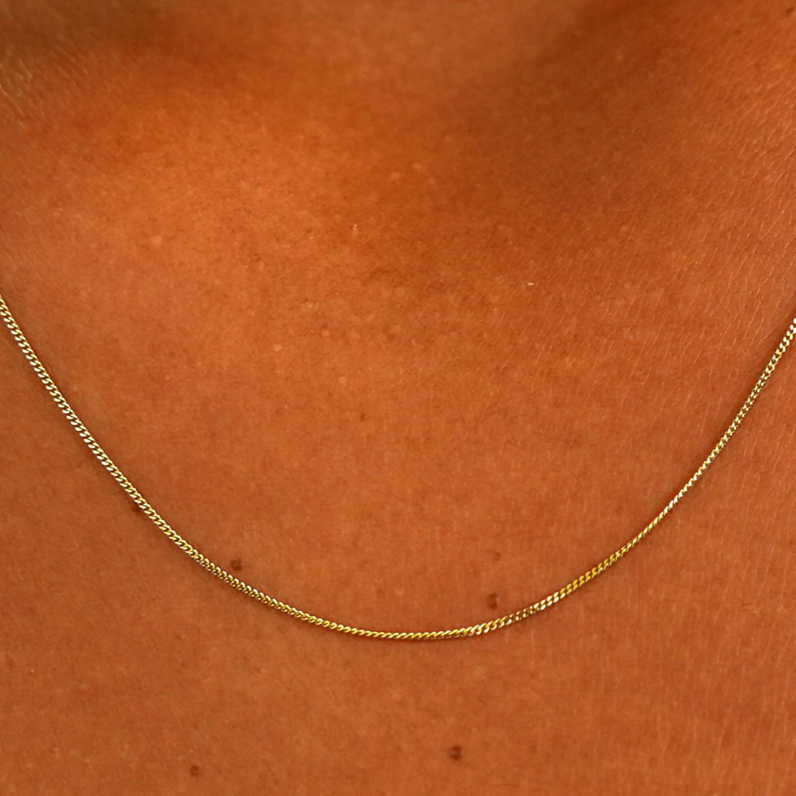 Close up view of a model's neck wearing a solid 14k yellow gold Essential Chain