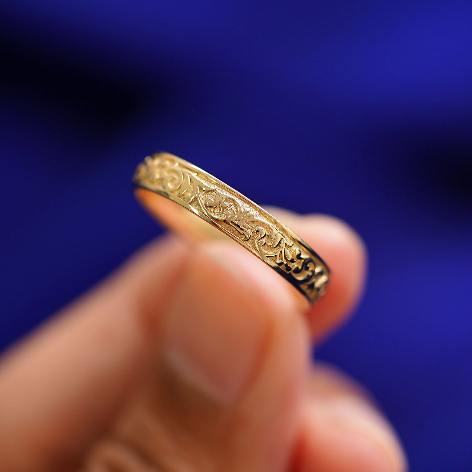 A model holding a 14k gold Filigree Band between their finger tips to show filigree detailing