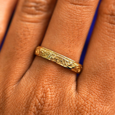 Close up view of a model's hand wearing a yellow gold Filigree band