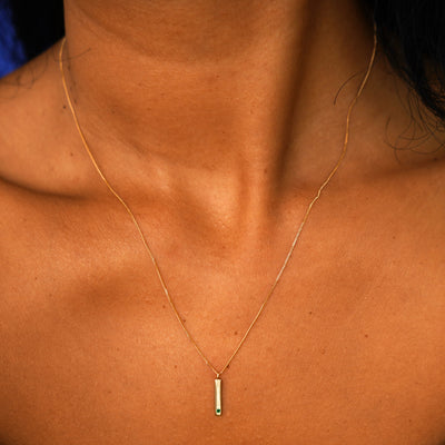 A model's neck wearing a solid yellow gold emerald Gemstone Bar Necklace
