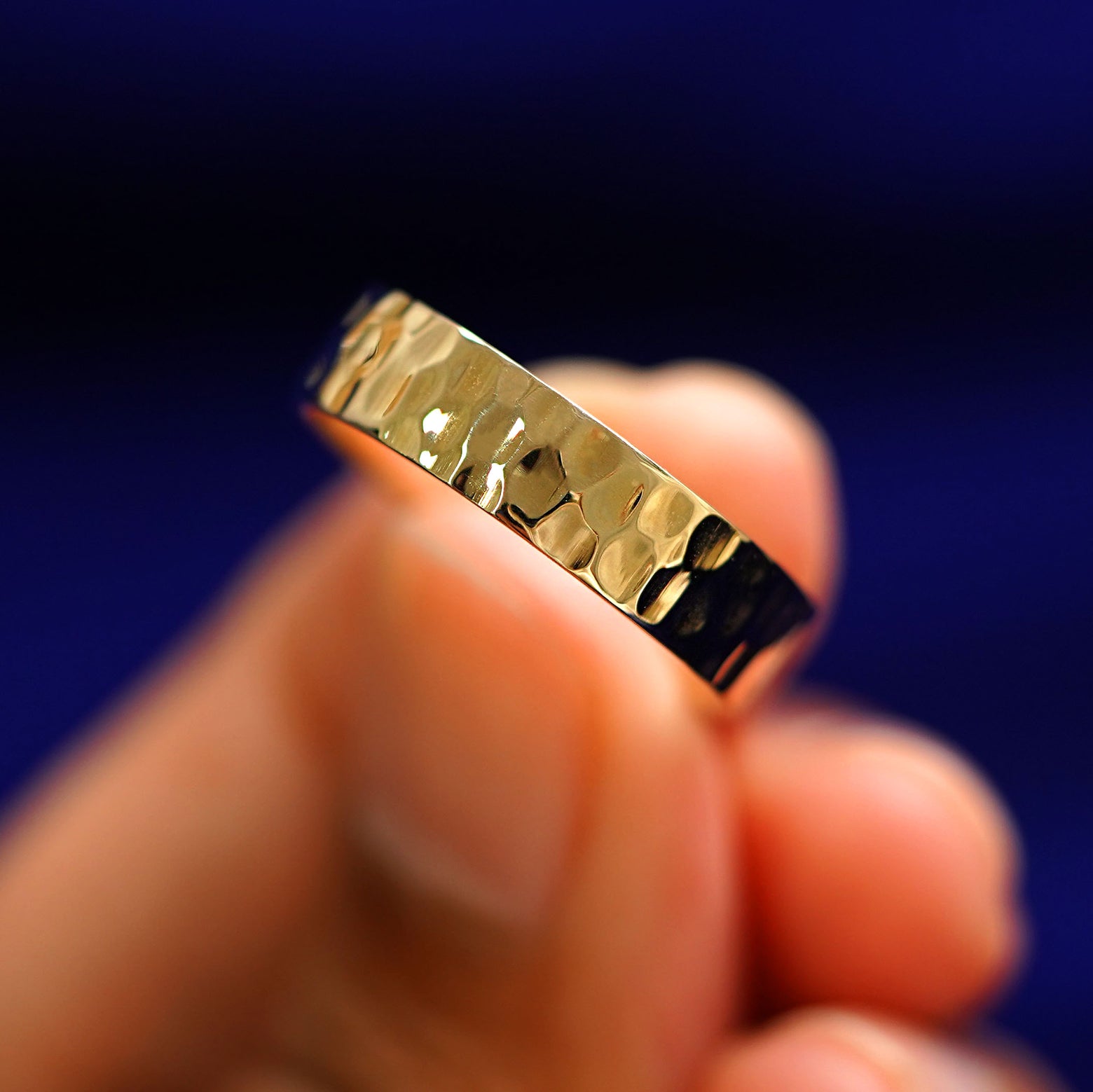 A model holding a Industrial Hammered Band tilted to show the side of the ring