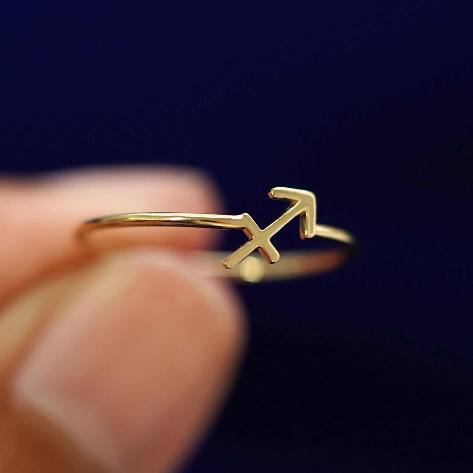 A model holding a Sagittarius Horoscope Ring tilted to show the detail of the zodiac sign